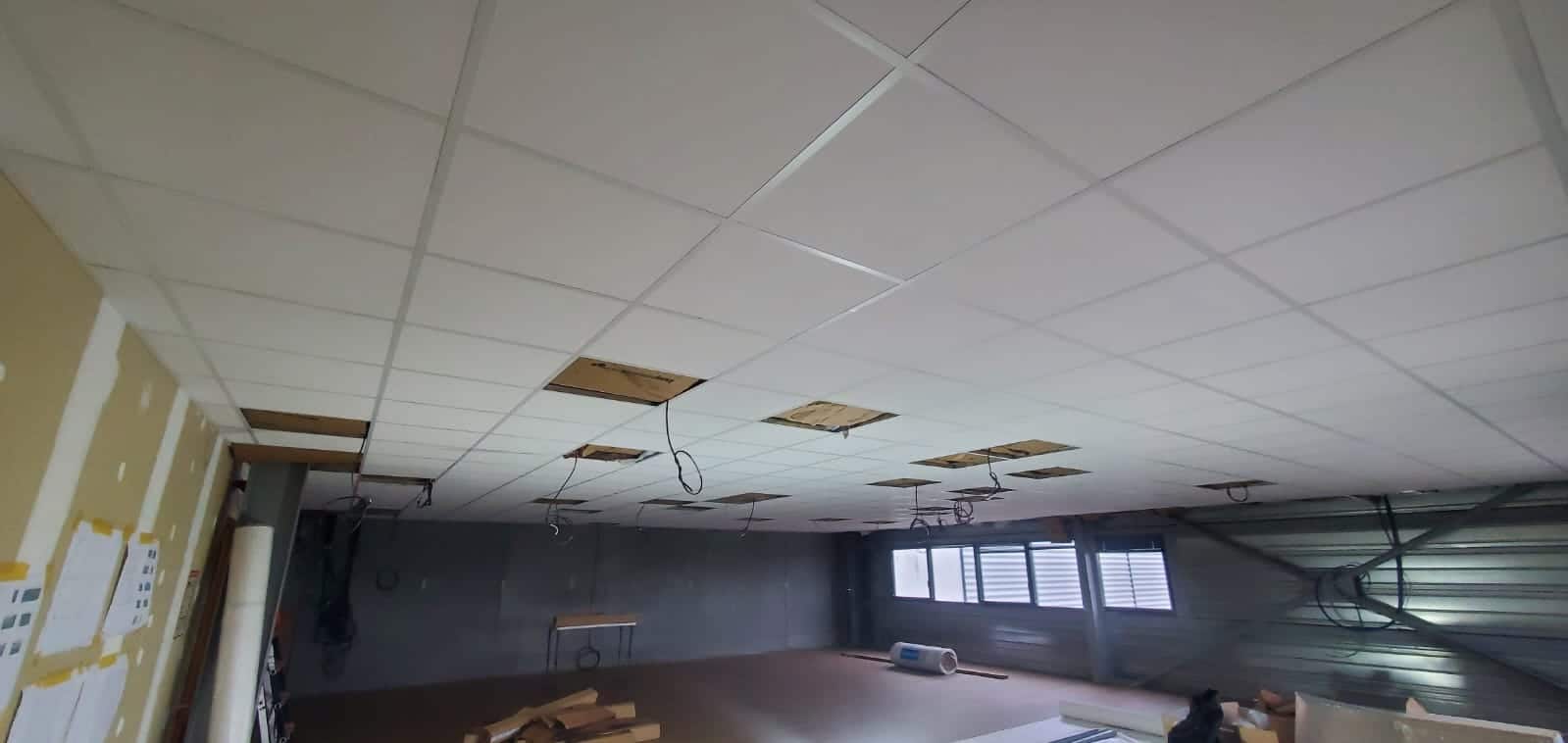 Détail de la pose d'une ossature métallique pour plafond modulaire démontable, garantissant un alignement parfait des dalles